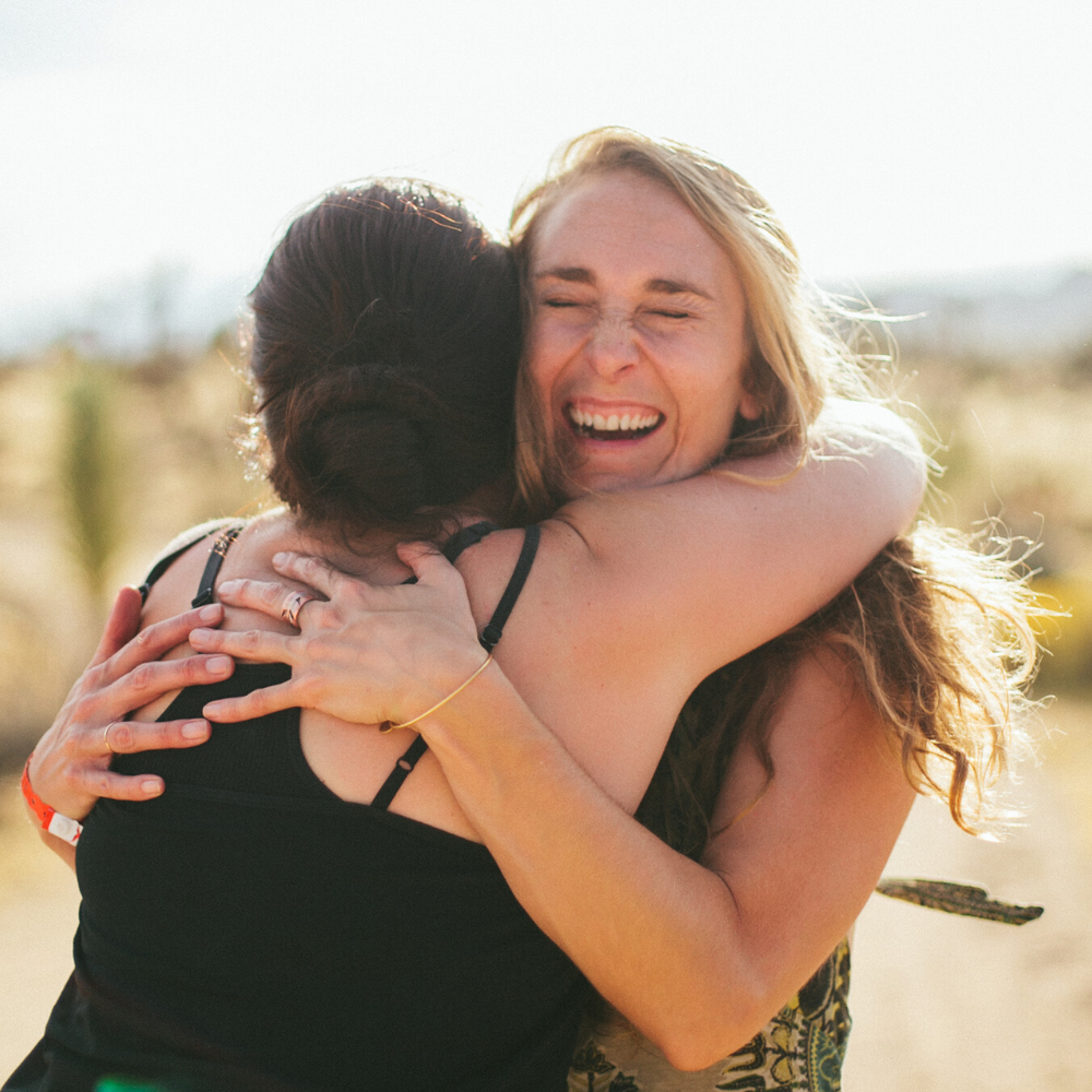 Two people sharing a warm embrace outdoors in golden light