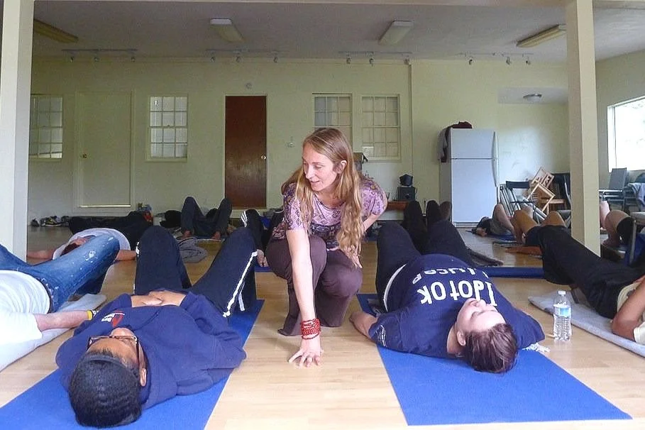 Jennica Mills guiding a group TRE session as participants rest on yoga mats
