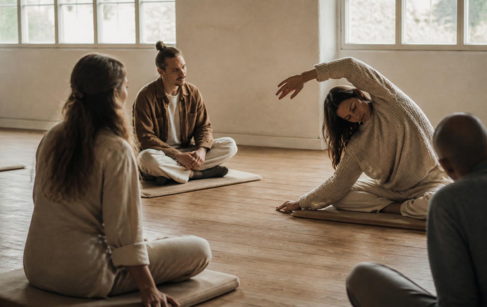 A small group practicing together on mats in a sunlit studio
